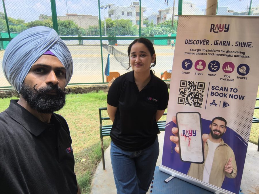 RAYY team members beside a RAYY standee at a partner venue